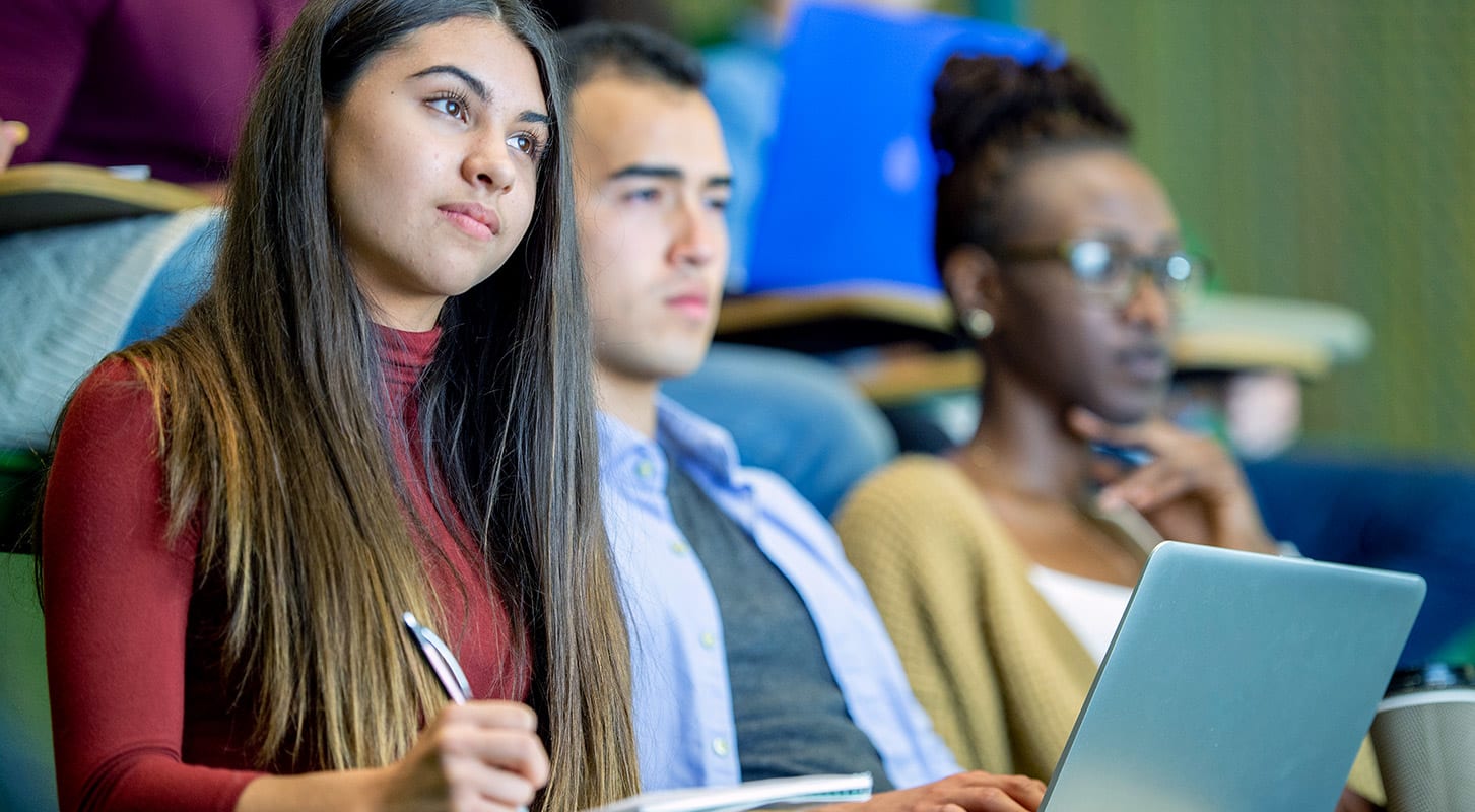 A classroom scene with students engaged in a lecture, seated in rows within a spacious lecture hall.